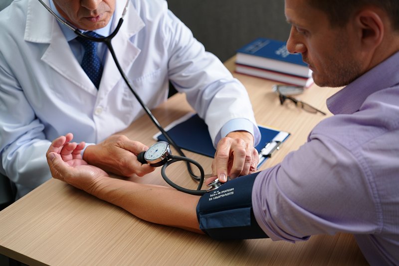 Врач измеряет давление пациента